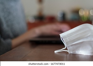 Medical Mask On Table And Woman Working From Home. Concept Of Prevention, Quarantine, COVID-19, Stay Home.