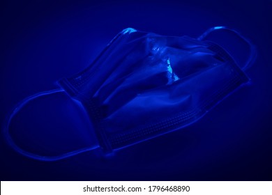 Medical Mask Under The Black Ultraviolet Light To Detect Germ On The Mask, UV Light Will Show The Hidden Germ On The Mask Like Glowing In The Dark, Sickness From Covid 19 Concept