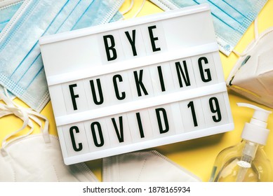 Medical Masks And Sanitizer Bottle With Lightbox With The Word Bye Fucking Covid-19 On A Yellow Background.Coronavirus Epidemic Concept