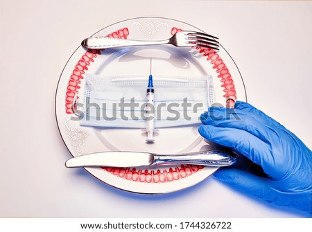 Medical meal, woman hand in a blue latex glove. Fork and knife lay on the dinner plate with syringe and protective mask. Flat lay, virus concept.