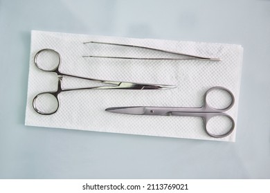 Medical Minor Set With Surgical Scissor, Tweezers, And Clamp Lie On A Napkin.