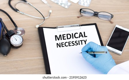 Medical necessity text is written by the hand of a jerk on a white sheet of paper on a table - Shutterstock ID 2195912623