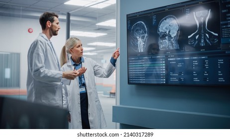 Medical Neuroscience Hospital Lab Meeting: Diverse Team Of Neurosurgeon And Neurologist Analyze TV Screen Showing MRI Scan With Brain Images, Talk About Sick Patient Treatment Method, New Drugs Cure