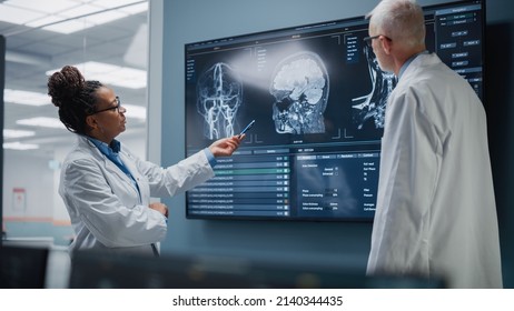 Medical Neuroscience Hospital Lab Meeting: Diverse Team Of Neurosurgeon And Neurologist Analyze TV Screen Showing MRI Scan With Brain Images, Talk About Sick Patient Treatment Method, New Drugs Cure