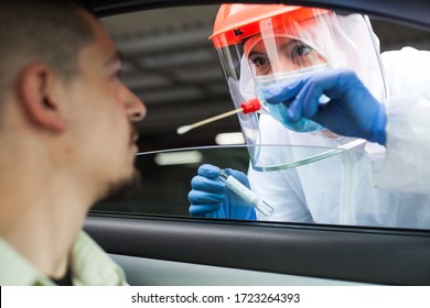 Medical NHS UK worker performing drive-thru COVID-19 check,taking nasal swab specimen sample from male patient through car window,PCR diagnostic for Coronavirus presence,doctor in PPE holding test kit - Shutterstock ID 1723264393