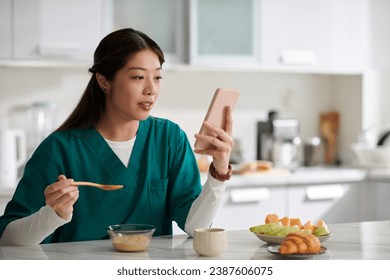 Medical nurse eating muesli for breakfast and reading news on social medial - Powered by Shutterstock