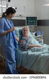 Medical Nurse Explaining Chest X-ray Radiography To Elderly Patient, Breathing With Help From Oxygen Mask Because Of Respiratory Illness. Getting Medicine Through Iv Drip Bag.