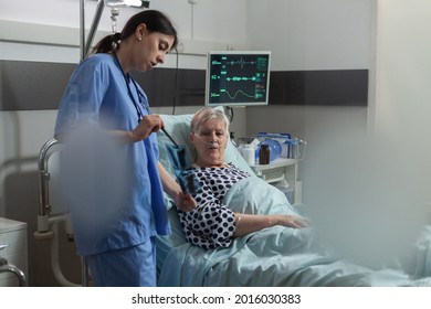 Medical Nurse Explaining Chest X-ray Radiography To Elderly Patient, Breathing With Help From Oxygen Mask Because Of Respiratory Illness. Getting Medicine Through Iv Drip Bag.