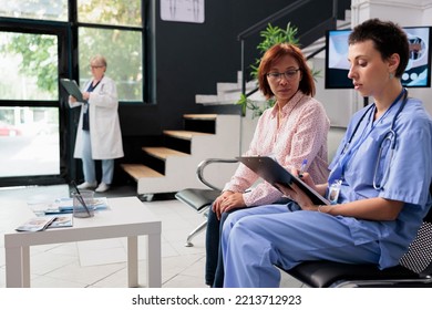 Medical Nurse Filling In Report Papers With Asian Patient, Doing Healthcare Consultation Hospital Waiting Room. Assistant Writing Checkup Form Documents Before Appointment. Medicine Concept