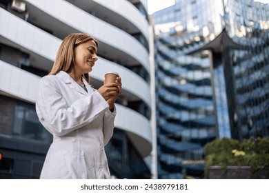 Medical nurse, woman, coffee and outdoor with thinking, vision or ideas for healthcare career. Young doctor, park and nature for walk, drink tea and mindset on path, wellness or clinic job - Powered by Shutterstock