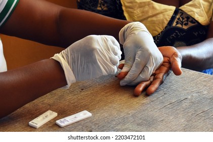 Medical Outreach Nonprofit Charity Organization Health Worker With Patient In Ghana, East Africa Doing A Finger Prick For HIV And Malaria Blood Testing Kits