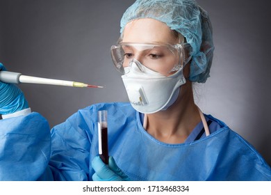 Medical Pathologist Or Research Scientist Wearing Protective Mask, Goggles And Gloves And Gown Working In A Lab With A Patient Blood Sample.  Using A Pipette For Sample Analysis