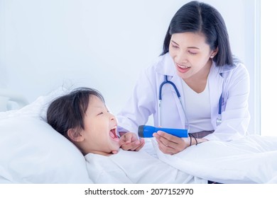 Medical Pediatrician Doctor In White Uniform Gown Use Hand Open Mouth Of Children, She Use Flashlight And Diagnosis In Hospital.