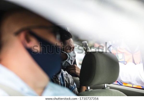 A\
Medical personnel scans temperature of a users vehicles as the\
government imposed large-scale restrictions to prevent the spread\
of the COVID-19 in Bandung, Indonesia, April,\
2020