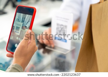 Medical pharmacy and contactless payment concept. Asian woman patient customer using mobile phone scan QR code on counter making online baking payment buying medicine and supplements in drugstore.