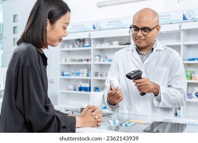 Medical pharmacy and healthcare. Handsome asian male pharmacist wearing lab coat using barcode scanner for selling medicine to customer under prescription order in the pharmacy drugstore. - Powered by Shutterstock