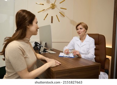 Medical Physician, Doctor In White Medical Gown, General Practitioner Working In Hospital Writing A Prescription To A Young Female Patient. Healthcare And Medical Concept