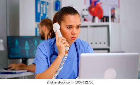 Medical practitioner answering phone calls and scheduling appointments in hospital. Healthcare physician in medicine uniform, receptionist doctor assistant helping with telehealth communication - Powered by Shutterstock