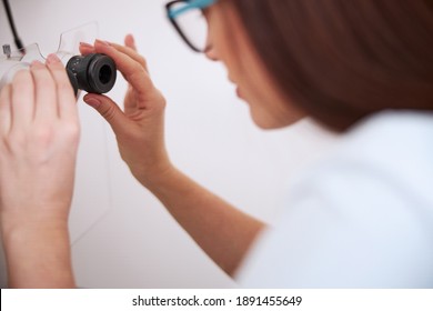 Medical practitioner gently turning the oculars of a slit lamp while tuning their accuracy - Powered by Shutterstock