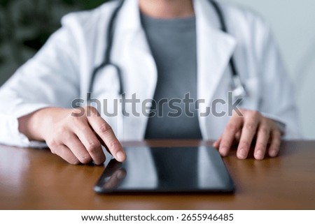 Medical practitioner using touchscreen tablet in office for electronic health records, digital diagnostics, patient data entry, and healthcare technology implementation in modern clinical practice.