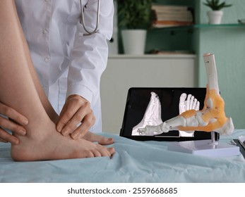 Medical professional examining foot anatomy with model and digital x-ray in clinic setting - Powered by Shutterstock