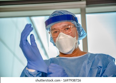 A medical professional, nurse, doctor, respiratory therapist puts gloves on in preparation of treating an influenza like illness, like Covid-19. 