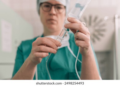 Medical professional in surgical attire preparing intravenous IV drip for venous access in a clinical setting - Powered by Shutterstock