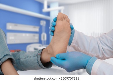 A medical professional wearing blue gloves examines a patient's foot in a clinical setting, focusing on foot health or podiatry. - Powered by Shutterstock