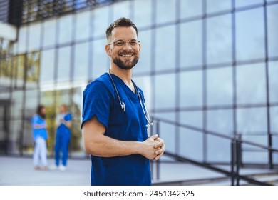 Medical professional working in a hospital. He is dressed in scrubs looking at the camera smiling with a stethoscope around his neck. Young male nurse home caregiver  - Powered by Shutterstock