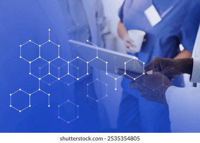 Medical professionals discussing data on a tablet. Doctors in blue scrubs, lab coats. Medical technology, healthcare, teamwork in a clinical setting. Medical data overlay technology. - Powered by Shutterstock