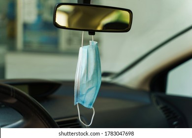 Medical protective face mask in car on the rearview mirror in day - Covid-19 pandemic protection on rear view in the vehicle - coronavirus epidemic new normal prevention concept - Shutterstock ID 1783047698