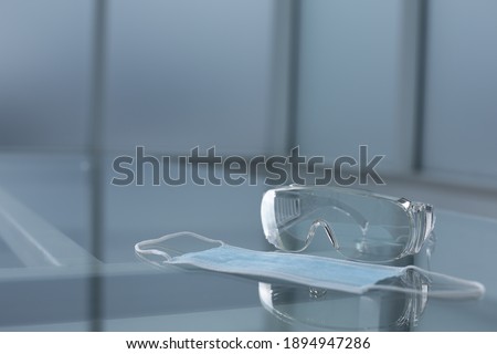 Medical protective mask and goggles on glass table