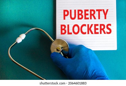 Medical and puberty blockers symbol. Words 'puberty blockers' on white note. Doctor hand in blue glove and stethoscope. Beautiful white background. Copy space. Medical and puberty blockers concept. - Shutterstock ID 2064601883
