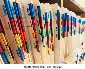 Medical Records Of Patients In Numbered And Color Coded Folders Are Organized And Arranged Numerically And Sequentially In Open Shelves Of A Clinic.