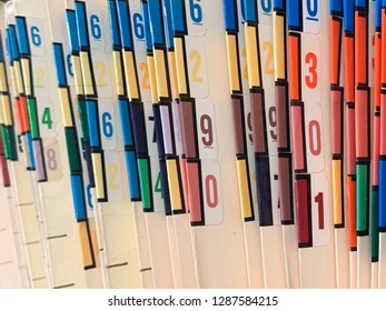 Medical Records Of Patients In Numbered And Color Coded Folders Are Organized And Arranged Numerically And Sequentially In Open Shelves Of A Clinic.