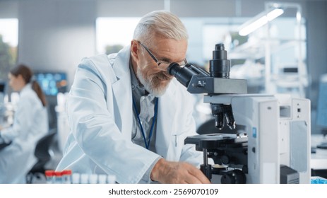 Medical Research and Development Laboratory: Senior Caucasian Male Scientist in Glasses Looking at a Sample in a Petri Dish Under a Microscope in an Advanced Biotechnology Lab