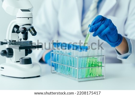 Medical research laboratory asian people male scientist working and analysing liquid biochemicals in laboratory flask.