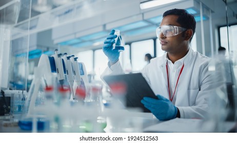 Medical Research Laboratory: Portrait of a Handsome Male Scientist Using Digital Tablet Computer, Analysing Liquid Biochemicals in a Laboratory Flask. Advanced Scientific Biotechnology Laboratory. - Shutterstock ID 1924512563
