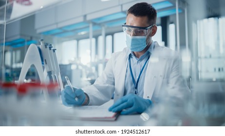 Medical Research Laboratory: Portrait Of Scientist Wearing Face Mask Analysing Biochemicals, Writing Down Information. Advanced Scientific Lab For Medicine, Biotechnology, Microbiology Development