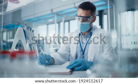 Medical Research Laboratory: Portrait of Scientist Wearing Face Mask Analysing Biochemicals, Writing Down Information. Advanced Scientific Lab for Medicine, Biotechnology, Microbiology Development