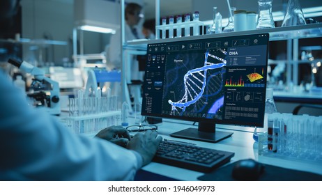 Medical Research Scientist Working On Desktop Computer With Gene Analysis Software In Modern Science Research Laboratory. Lab Engineers In White Coats Conduct Experiments In The Background.