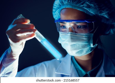 Medical researcher holding test tube with blue fluorescent liquid - Powered by Shutterstock