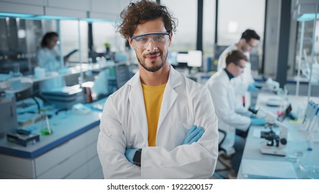 Medical Science Laboratory: Handsome Young Latin Scientist Wearing White Coat and Safety Glasses, Crossing Arms, Looking at Camera. Young Bio Technology Research Specialist. Medium Portrait Shot - Powered by Shutterstock