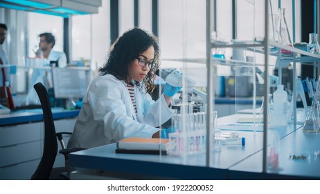 Medical Science Laboratory: Portrait Of Beautiful Black Scientist Is Using Microscope Does Analysis Of Test Sample. Ambitious Young Biotechnology Specialist, Working With Advanced Equipment