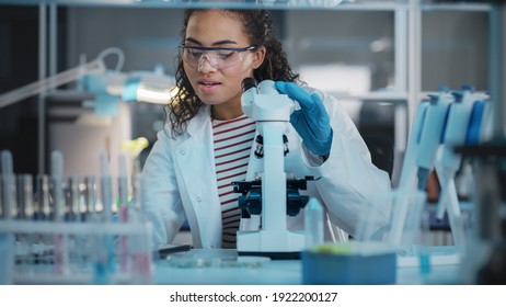 Medical Science Laboratory: Portrait Of Beautiful Black Scientist Using Microscope, Does Analysis Of Test Sample. Ambitious Young Biotechnology Specialist, Working With Advanced Equipment