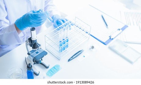 Medical or scientific researcher or man doctor looking at a test tube of clear solution in a laboratory - Powered by Shutterstock