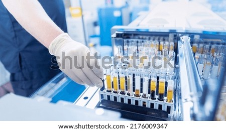 Medical scientist loading samples in robot machine for biochemical automatic testing blood laboratories.