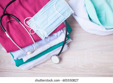 Medical Scrub Shirt With Stethoscope On Wooden Desktop.