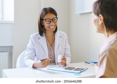 Medical services. Smiling african woman doctor holding white bottle of pills, prescribing medicine to female patient in clinic, friendly doc physician consulting client at medical checkup consultation - Powered by Shutterstock