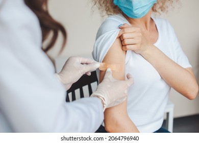 Medical sister sticking a patch on a young woman's arm after giving her the corona virus vaccine. Antiviral vaccine.